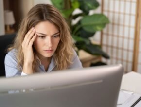 Miért ráng a szemhéjam napok óta, és mikor múlik el? Nő laptop előtt ül, szeméhez nyúl