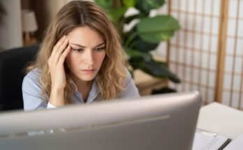 Miért ráng a szemhéjam napok óta, és mikor múlik el? Nő laptop előtt ül, szeméhez nyúl